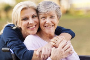 middle aged woman embracing disabled senior mother