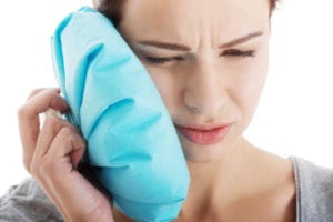 Young woman with toothache and ice bag.